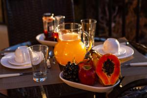 uma mesa com um prato de fruta e um jarro de sumo em Le Chalet Boutique em Campos do Jordão