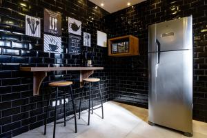 um bar com um frigorífico de aço inoxidável e paredes de tijolo preto em Le Chalet Boutique em Campos do Jordão