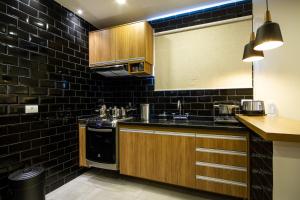 uma cozinha com paredes de azulejos pretos e armários de madeira em Le Chalet Boutique em Campos do Jordão