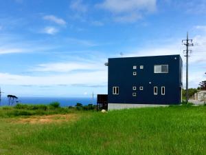 a blue building on the side of a grass field at Saraswati in Nakijin