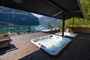 uma banheira de hidromassagem num deque com vista para um lago em Grande Fjord Hotel em Geiranger
