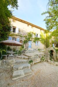 a stone house with a table and an umbrella at Mas des Baussiers in Saint-Martin-de-Castillon