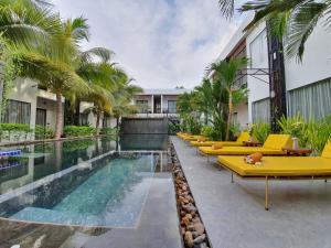 a swimming pool with yellow lounge chairs and a hotel at Central Corner d'Angkor in Siem Reap