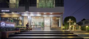 a man standing in front of a building at night at @Home Residence in Bangkok