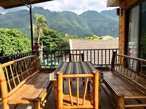 a wooden table on a balcony with mountains in the background at Mai Chau Green Ecohouse in Hòa Bình