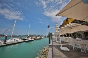 a dock with boats in a marina with tables and chairs at Resorts World Langkawi in Pantai Cenang