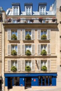an apartment building with white windows and a blue storefront at Hôtel des Arts Montmartre in Paris