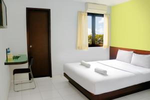 a bedroom with a white bed and a window at LeGreen Suite Ratulangi in Ambon