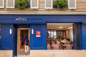 a woman walking in front of a hotel at H&ocirc;tel des Arts Montmartre in Paris