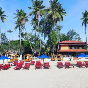 Blue Sand Beach Resort في ترينكومالي: صف من الكراسي الحمراء والمظلات الزرقاء على الشاطئ
