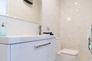 a white bathroom with a sink and a toilet at Aqua-Heights Apartment in Nelson