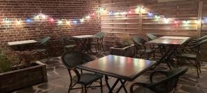 een restaurant met tafels en stoelen en verlichting op een bakstenen muur bij Auberge des Remparts in Péronne