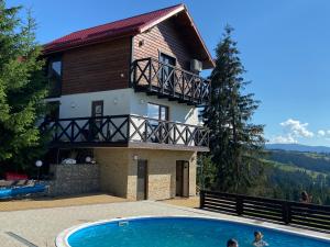 a villa with a swimming pool in front of a house at Panorama Karpat in Yablunytsya
