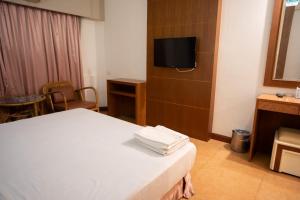 Cette chambre comprend un lit et une télévision. dans l'établissement โรงแรม เพนท์เฮ้าส์ รีสอร์ท เบตง, à Betong