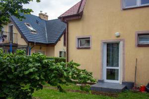 a yellow house with a white door and a yard at Domek letniskowy in Poddąbie