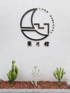 a sign on a wall with cactuses and a clock at Zhu Yue Guan in Jinning