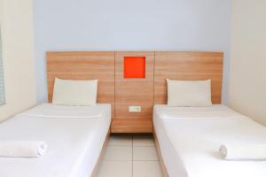 two beds in a small room with a red box on the wall at LeGreen Suite Waihaong in Ambon +12 photos