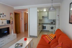a living room with an orange couch and a kitchen at As Basoñas in Porto do Son
