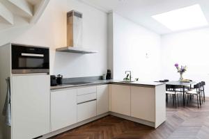 a kitchen with white cabinets and a table with chairs at Anegang Boutique Appartement in Haarlem
