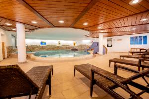 une grande piscine intérieure avec des bancs et une aire de jeux dans l'établissement Hotel Engel - Familotel Hochschwarzwald, à Todtnauberg