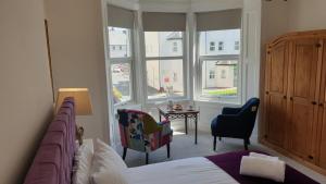 1 dormitorio con 1 cama, 2 sillas y ventanas en Snowdon Retreat Villa by Seaside Llandudno, en Llandudno