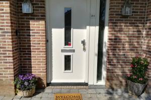 uma porta branca numa casa de tijolos com flores em cestos em Vakantiehuis Horsterwold em Zeewolde