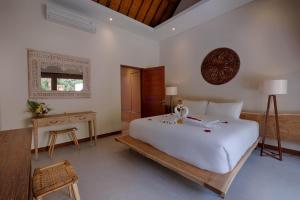 ein Schlafzimmer mit einem großen weißen Bett und einem Tisch in der Unterkunft Kutus Kutus Mas Ubud Villa in Ubud