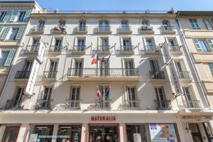 a large white building with flags in front of it at Hotel Florence Nice in Nice