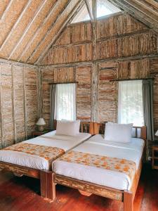 - 2 lits dans une chambre dotée de murs en bois et de fenêtres dans l'établissement Umah Kayu Ubud, à Ubud