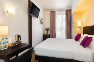 a hotel room with a large bed and a desk at Hotel Florence Nice in Nice