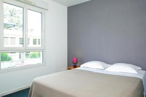 Habitación blanca con cama y ventana en Séjours & Affaires Annecy Le Pont Neuf, en Annecy
