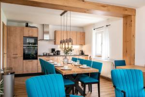 a kitchen and dining room with a wooden table and blue chairs at AmThumersbach in Zell am See
