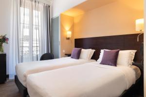 two beds in a hotel room with purple pillows at Hotel Florence Nice in Nice