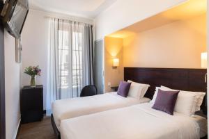 two beds in a hotel room with purple pillows at Hotel Florence Nice in Nice