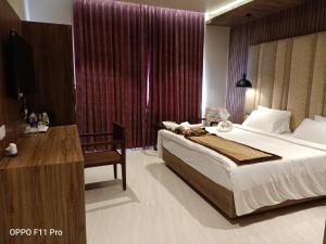BalāngīrThe Hotel Celebration的一间带床和书桌的酒店房间和一张床 sidx sidx