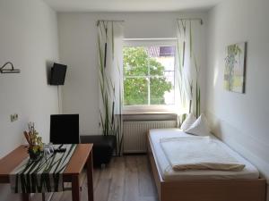 um quarto com uma cama, uma mesa e uma janela em Landgasthof Braun em Mindelstetten