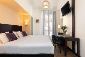 a bedroom with a bed and a desk and a television at Hotel Florence Nice in Nice