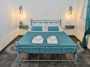 a bedroom with a blue bed with towels on it at Family Villages Santorini in Vlychada Beach