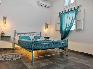 a bedroom with a bed with blue sheets and a window at Family Villages Santorini in Vlychada Beach +37 photos