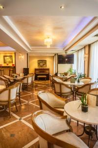 un restaurante con mesas, sillas y un piano en Park Hotel en Volos