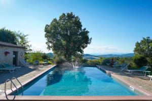 a swimming pool with a fountain in front of a house at Querceto Di Castellina in Castellina in Chianti
