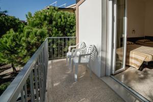 a balcony with two chairs and a bed at Hotel Sayonara in Milano Marittima