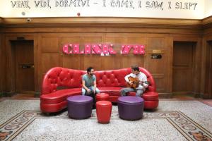 dos hombres sentados en un sofá rojo en una habitación en Clink78 Hostel, en Londres