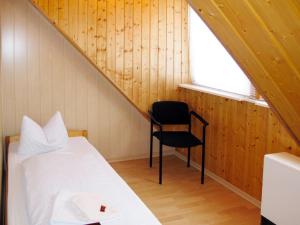 a bedroom with a bed and a chair in a attic at Apartment Old Hüsung - MUZ320 by Interhome in Mirow