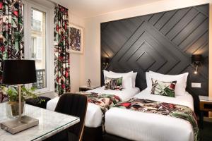 une chambre d'hôtel avec deux lits et une table dans l'établissement Hôtel des Arts Montmartre, à Paris