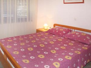 a bed with a purple comforter with yellow and white flowers at Apartment Blazina - LBN101 by Interhome in Ravni