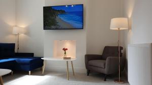 ein Wohnzimmer mit einem Tisch und einem TV an der Wand in der Unterkunft Snowdon Retreat Villa by Seaside Llandudno in Llandudno
