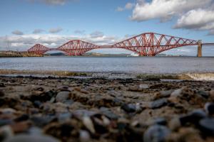 a bridge over a body of water with a train on it at Orocco Pier in Queensferry