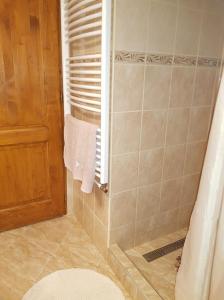 uma casa de banho com um chuveiro, toalhas e uma porta em Napocska Vendégház Harkány em Harkány