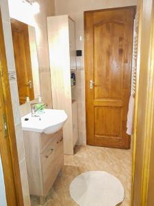 La salle de bains est pourvue d'un lavabo et d'une porte en bois. dans l'établissement Napocska Vendégház Harkány, à Harkány